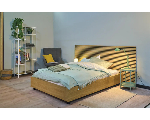 Chambre claire avec lit en bois, lampe de chevet, étagère et fauteuil