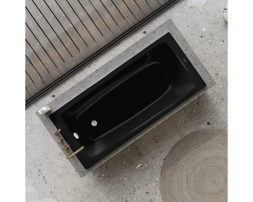 Baignoire noire dans salle de bain avec plafond à poutres en bois et sol en pierre