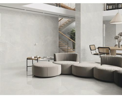 Heller Wohnraum mit großformatigen Fliesen an Boden und Wand, Treppe im Hintergrund