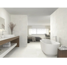 Salle de bains lumineuse avec baignoire, lavabo et accès à la chambre
