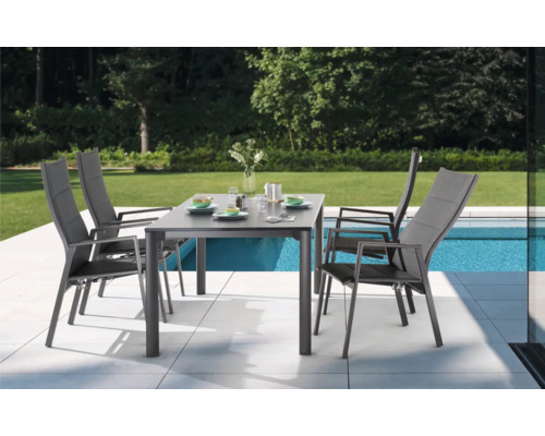 Scène de jardin avec table à manger et quatre chaises en aluminium.