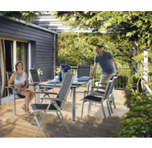 Esstischgruppe mit Tisch und Stühlen auf einer Terrasse unter einer Pergola.