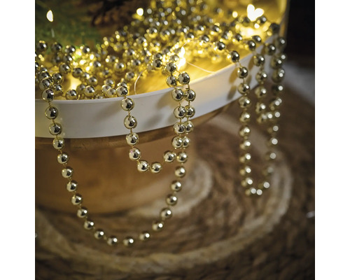 Goldfarbene Perlenkette zur Dekoration in einer Schale