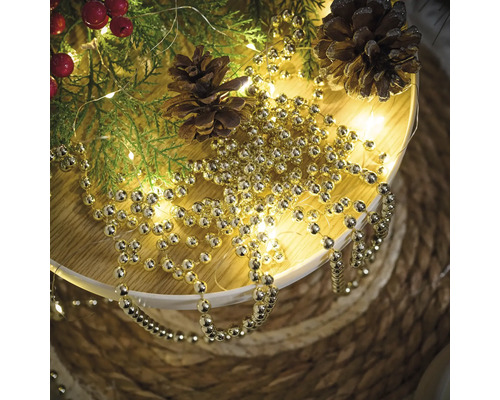 Dekoration mit Tannenzweigen, Zapfen und goldfarbener Kugelkette