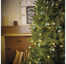 Sapin de Noël décoré avec éclairage et boules près d''une cheminée