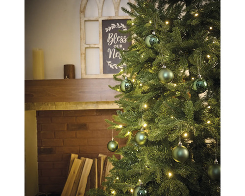 Sapin de Noël décoré avec éclairage et boules près d''une cheminée