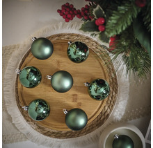 Boules de Noël décoratives vertes sur une assiette en bois