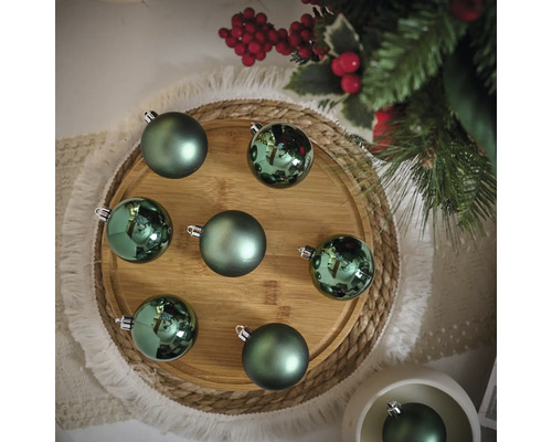 Boules de Noël décoratives vertes sur une assiette en bois