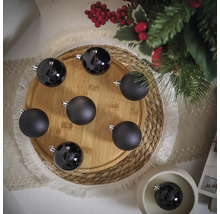 Dekorative schwarze Weihnachtskugeln auf einem Holzteller