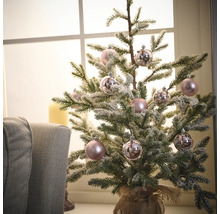 Sapin de Noël miniature décoré avec des boules dans un sac de jute