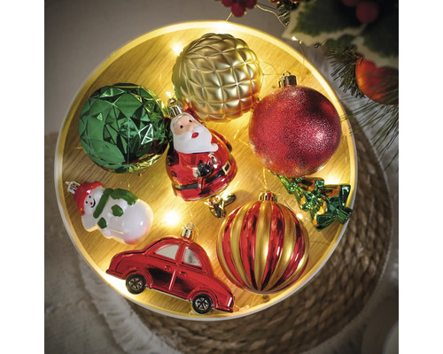 Boules de Noël décoratives et figurines sur un plateau avec des lumières.