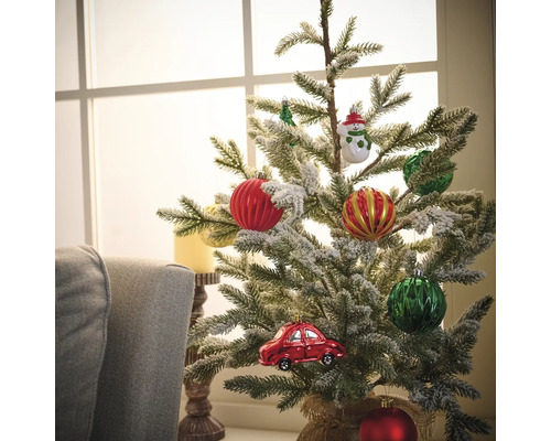 Sapin de Noël décoré avec des boules de Noël et une décoration de voiture devant une fenêtre