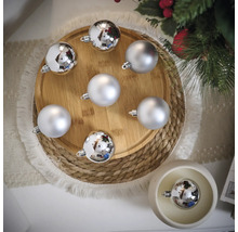 Boules de Noël décoratives argentées sur une assiette en bois et une table