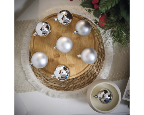 Boules de Noël décoratives argentées sur une assiette en bois et une table