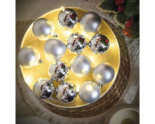 Boules de Noël argentées sur un plateau en bois illuminé