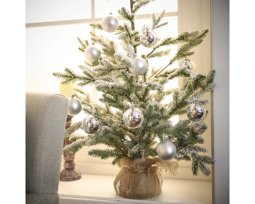Petit sapin de Noël artificiel décoratif avec boules argentées dans un sac de jute