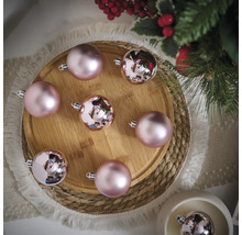 Arrangement de boules de Noël roses sur une assiette en bois avec des branches de sapin et des décorations