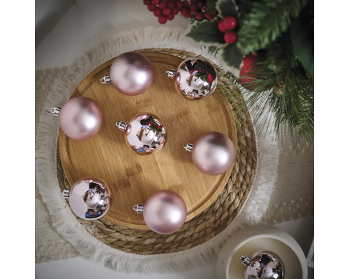 Arrangement de boules de Noël roses sur une assiette en bois avec des branches de sapin et des décorations