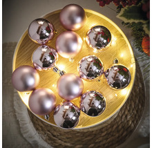 Boules de Noël décoratives roses sur un plateau en bois avec des lumières