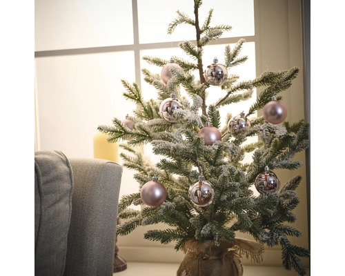 Petit sapin de Noël décoré avec des boules de Noël devant une fenêtre
