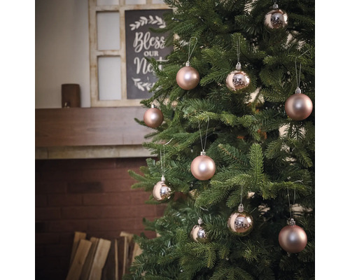 Sapin de Noël décoré avec boules devant la cheminée