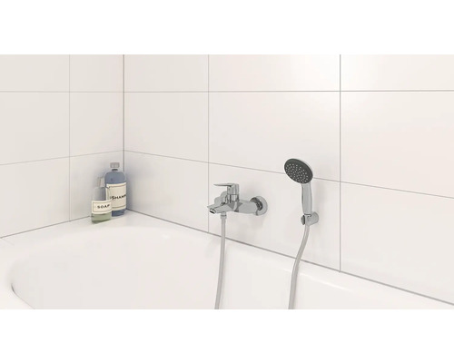 Salle de bain avec baignoire, robinet et douchette, ainsi que savon et shampoing