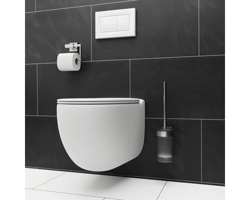 WC suspendu avec plaque de commande, support papier toilette et brosse de toilette sur un mur carrelé