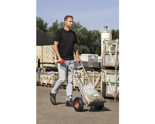 Mann transportiert Sackware mit einer Sackkarre im Außenbereich