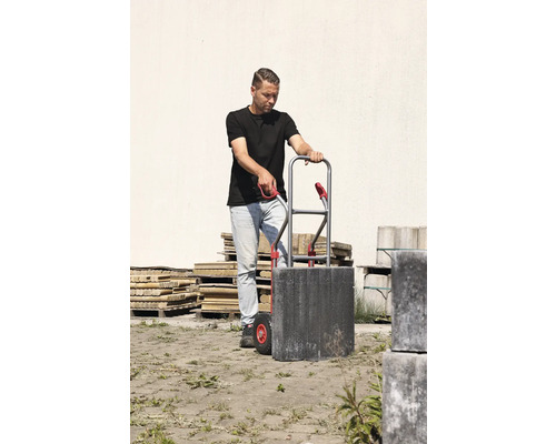 Un homme transporte des pavés avec un diable.