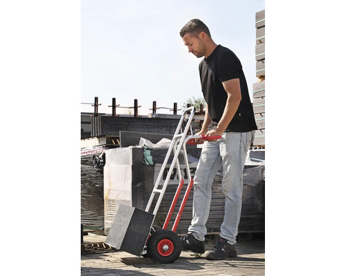 Mann transportiert Pflastersteine mit einer Sackkarre.