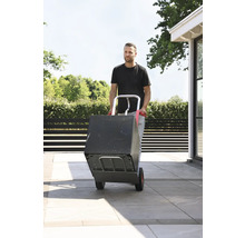 Mann transportiert Kiste mit einer Sackkarre im Aussenbereich.