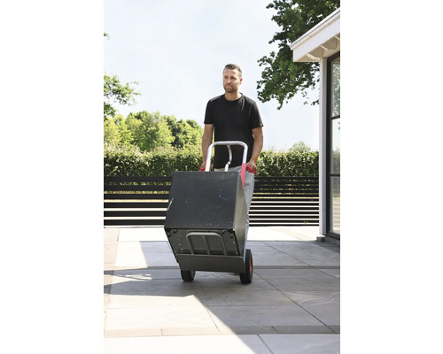 Mann transportiert Kiste mit einer Sackkarre im Aussenbereich.