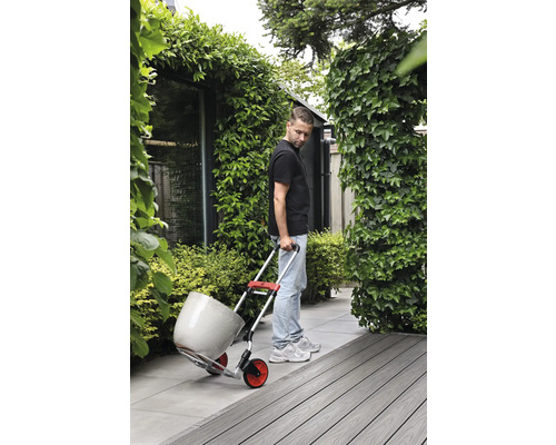 Mann transportiert Blumentopf mit einer Sackkarre im Garten.