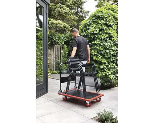 Une personne transporte des chaises dans le jardin avec une planche à roulettes.