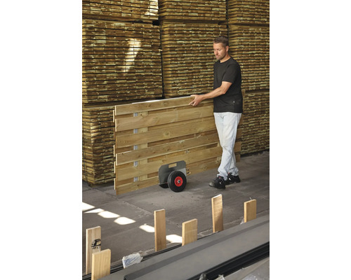 Mann transportiert Holzzaunelement mit Transportwagen