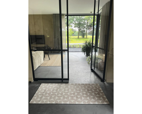 Intérieur avec tapis, portes en verre et vue sur le jardin.