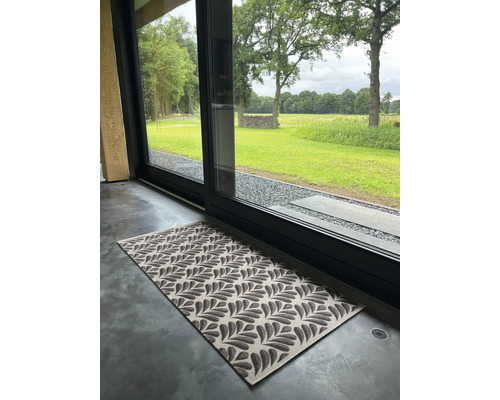 Paillasson à motif de feuilles devant une porte coulissante