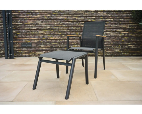 Gartenstuhl mit Fußhocker vor Ziegelwand