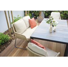 Scène de jardin avec canapé, coussins et table à manger sur une terrasse