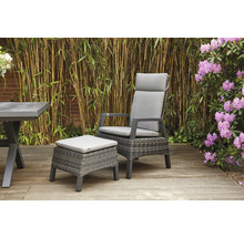 Gartenszene mit Rattansessel, Fusshocker und Tisch auf einer Holzterrasse