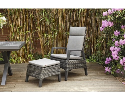 Gartenszene mit Rattansessel, Fusshocker und Tisch auf einer Holzterrasse