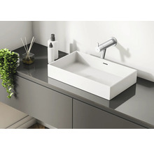 Salle de bain moderne avec lavabo, robinet, bâtonnets parfumés et distributeurs de lotion sur un meuble-lavabo gris.