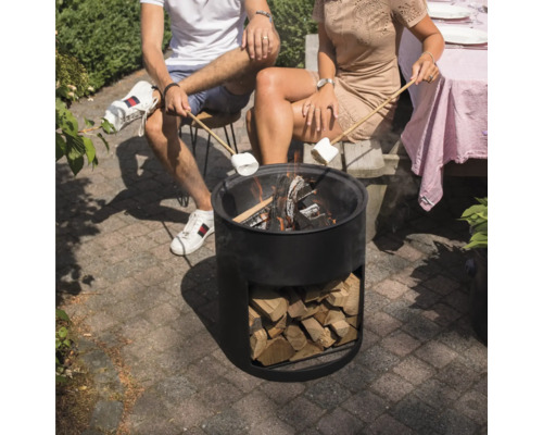 Personen sitzen um eine Feuerstelle und halten Marshmallows über die Flammen