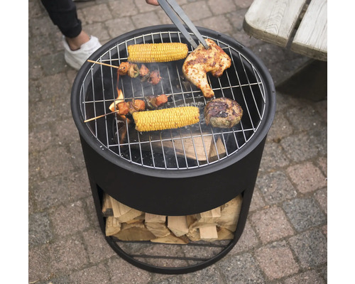 "Ein Holzkohlegrill mit Grillgut wie Hähnchen, Maiskolben und Fleischspießen wird mit einer Grillzange gewendet