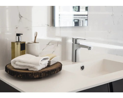 Lavabo de salle de bains avec robinet, distributeur de savon, brosse à dents et serviettes sur plateau en bois