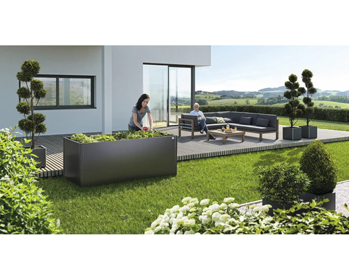 Scène de jardin avec une femme plantant un potager surélevé, un coin salon et des bacs à plantes décoratifs sur une terrasse.