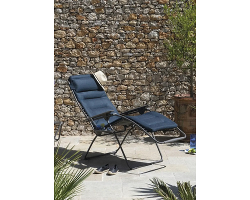 Gartenszene mit einem Liegestuhl mit Fußstütze, einem Hut und Schuhen