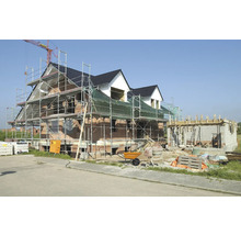 Neubau eines Hauses mit Gerüst, Zementmischer und Baumaterialien.