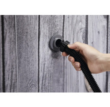 Une main connecte un tuyau au raccord mural