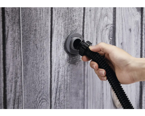 Une main connecte un tuyau au raccord mural